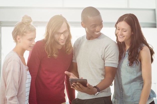 Homem sorridente que mostra um tablet digital para colegas de trabalho