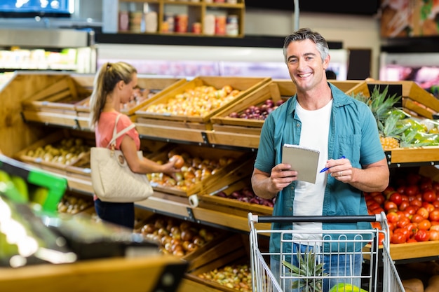 Homem sorridente segurando a lista de compras