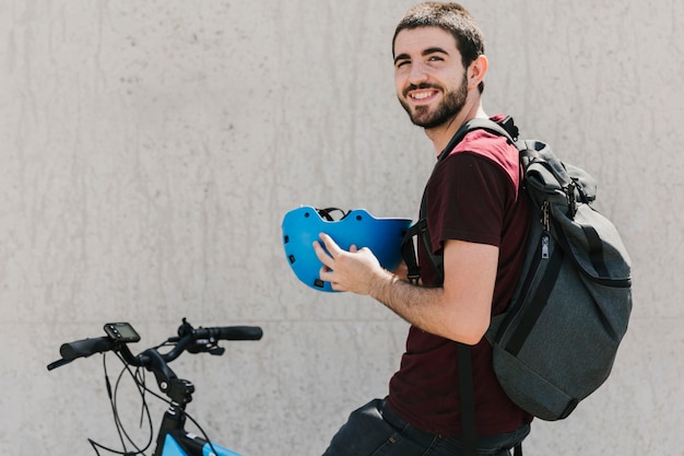 Homem sorridente, segurando, capacete, ligado, bicicleta