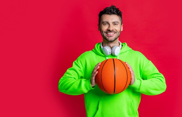 Homem sorridente segurando o estúdio de bola de basquete Jogador de basquete sorrindo isolado no vermelho