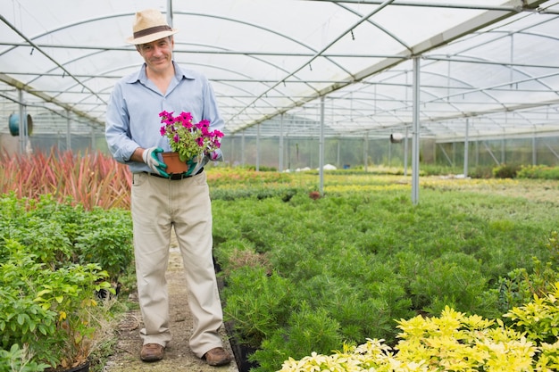 Homem sorridente segurando um pote de flores