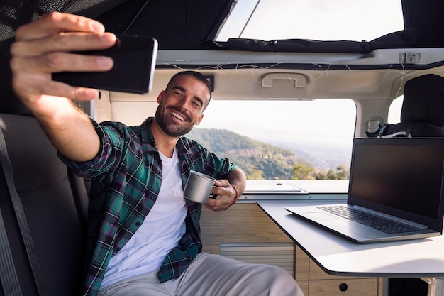 Homem sorridente tirando uma selfie dentro de sua van