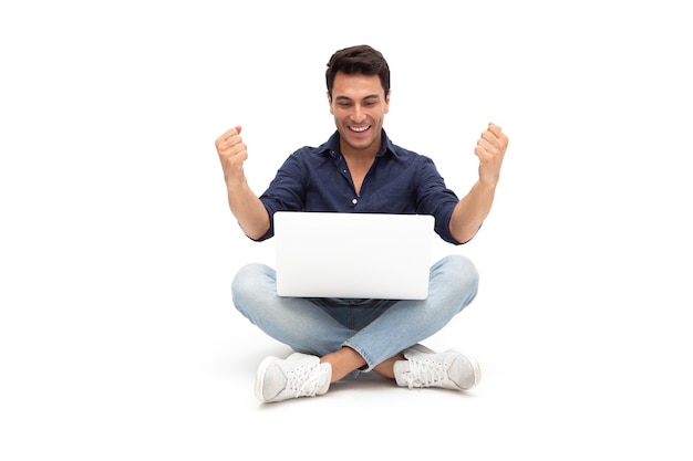 Homem sorridente usando laptop enquanto está sentado contra um fundo branco
