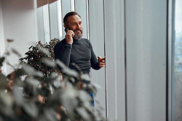 Homem sorridente usando telefone celular enquanto fala