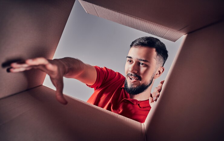 Foto homem sorrindo, abrindo a caixa e olhando dentro. o pacote, entrega, surpresa, presente e conceito de estilo de vida