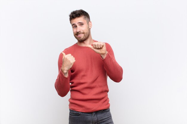 homem sorrindo alegremente e casualmente apontando para copiar o espaço ao lado, sentindo-se feliz e satisfeito