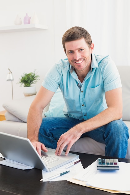 Homem sorrindo em um laptop em casa