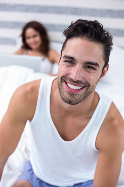 Homem sorrindo enquanto esposa sentada na cama