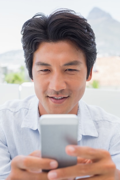 Homem sorrindo enviando uma mensagem de texto