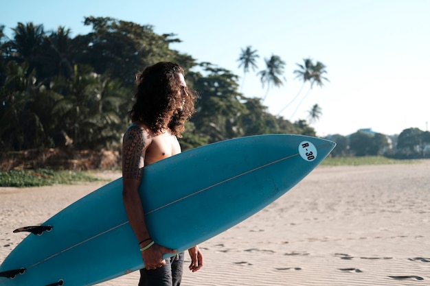 Homem surfista sentado na prancha de surfe na areia da praia