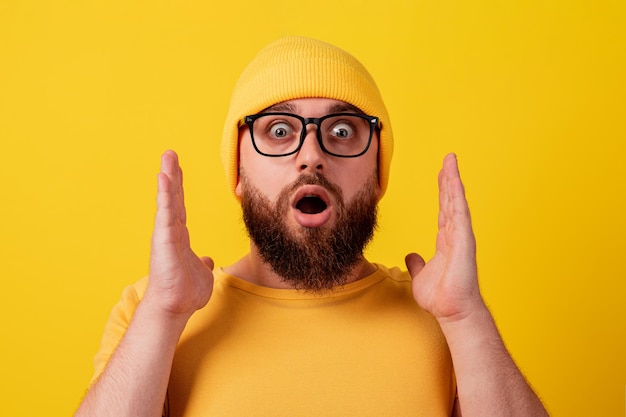Homem surpreso de óculos sobre fundo amarelo, emoção uau, conceito de promoções ou grandes descontos