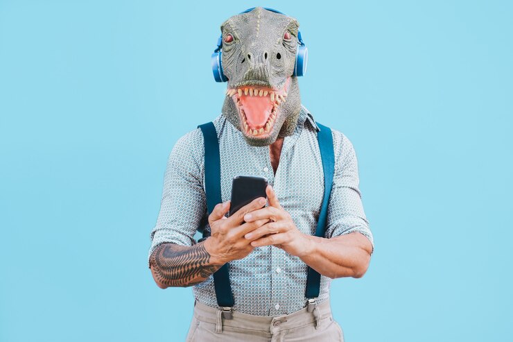 Foto homem tatuado sênior com máscara de t-rex usando smartphone enquanto ouve música