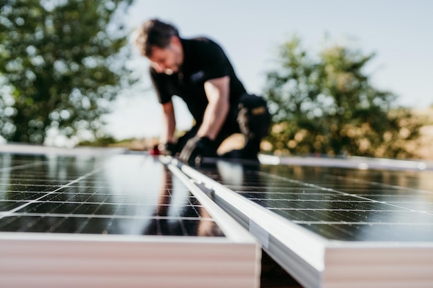 Homem técnico maduro montando painéis solares no telhado de uma casa para autoconsumo foco em primeiro plano