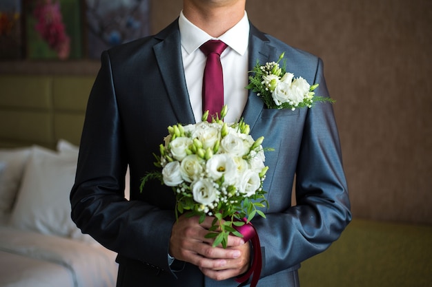 Homem tem um buquê de casamento nas mãos. O conceito de dia dos namorados. Conceito de casamento. O noivo com buquê. O noivo de terno tem um buquê de casamento bouquet.bridal.