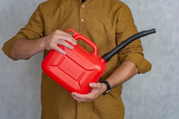 Homem tem uma botija de gás de plástico vermelho nas mãos.