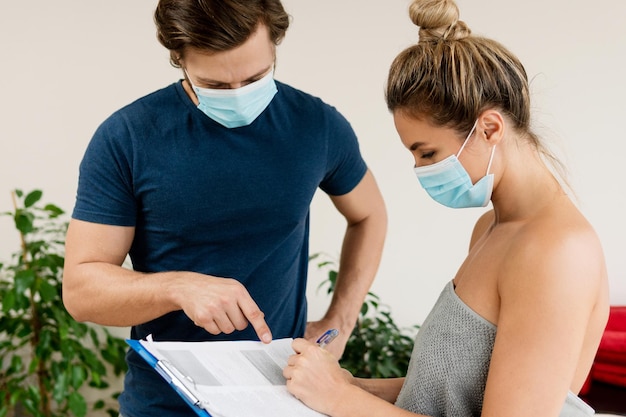 Homem terapeuta manual usando máscara de prevenção está trabalhando com uma cliente mulher na clínica de massagem