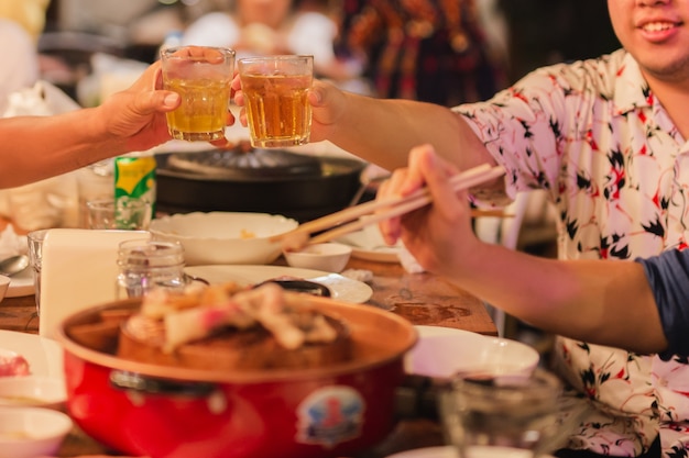 homem tilintar de copos com álcool comemorando o jantar em família.