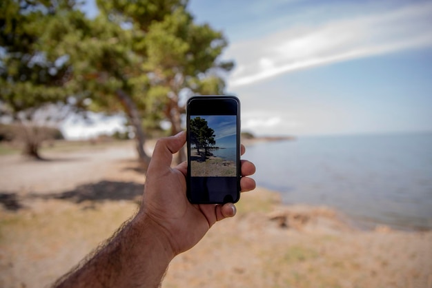 homem tira foto com smartphone na natureza