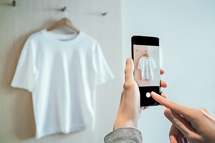 Foto homem tira foto no smartphone de roupas usadas para revenda.