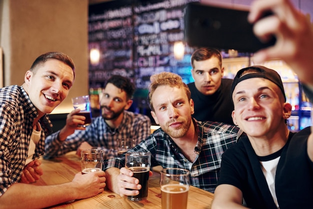 Homem tira selfie por telefone Grupo de pessoas juntas no pub se divertem no fim de semana
