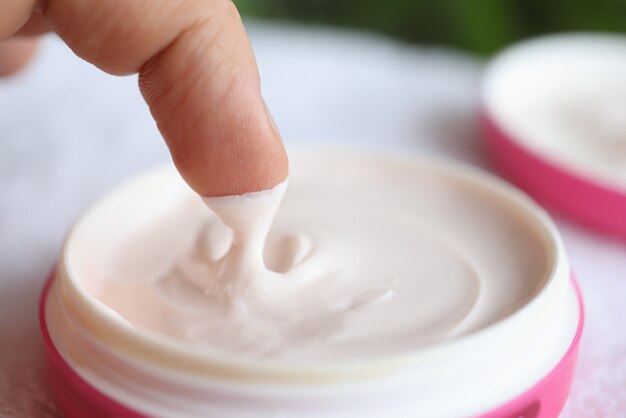 Homem tirando creme nutritivo do frasco, close-up