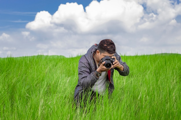 Homem tirando foto com a câmera no campo Fotógrafo no campo tirando uma foto