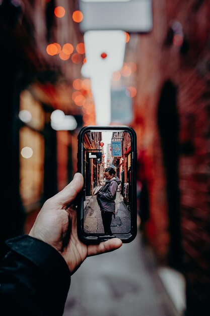 Homem tirando foto com celular de mulher no beco