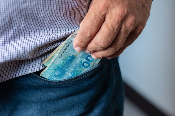 Homem tirando notas de 100 reais do bolso.