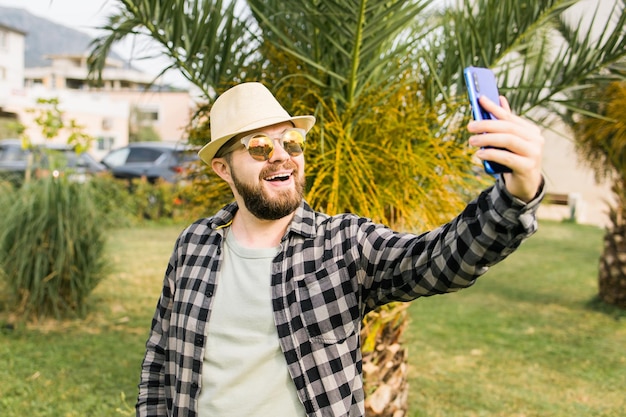 Homem tirando selfie retrato sobre o fundo da palmeira feliz cara do milênio aproveitando as férias de verão