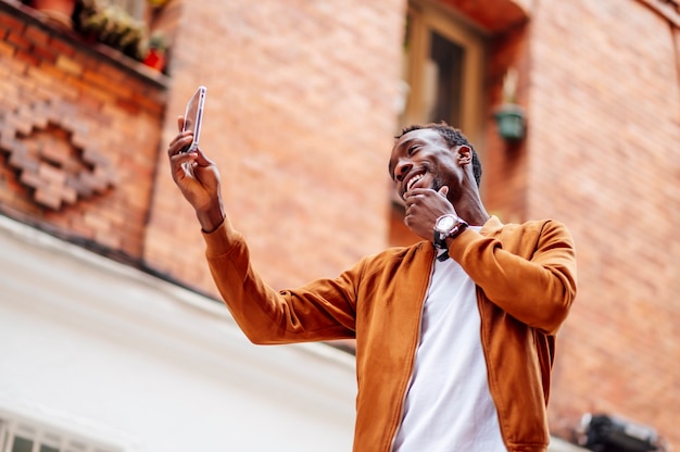 Foto homem tirando uma foto com o celular e tocando seu rosto