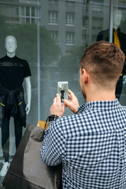 Homem tirando uma foto de uma vitrine de uma loja de moda