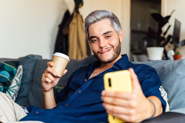 Homem tirando uma selfie e bebendo café