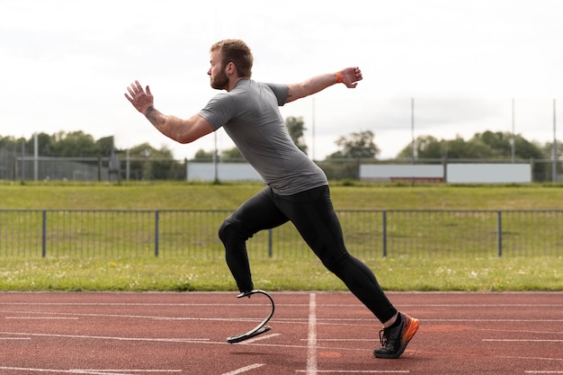 Homem tiro completo com prótese correndo na pista