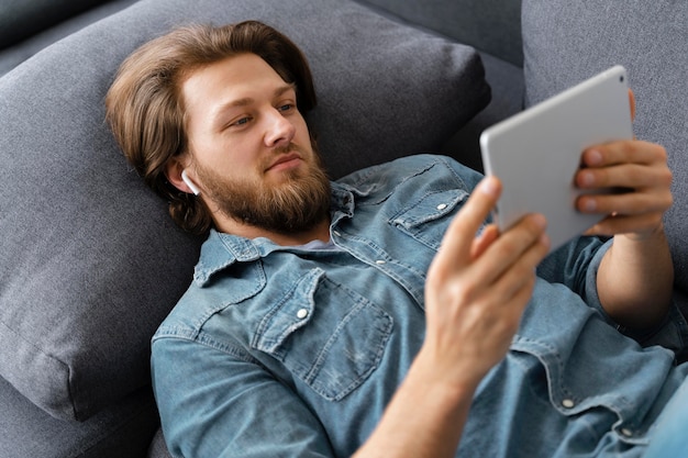 Foto homem tiro médio com tablet no sofá