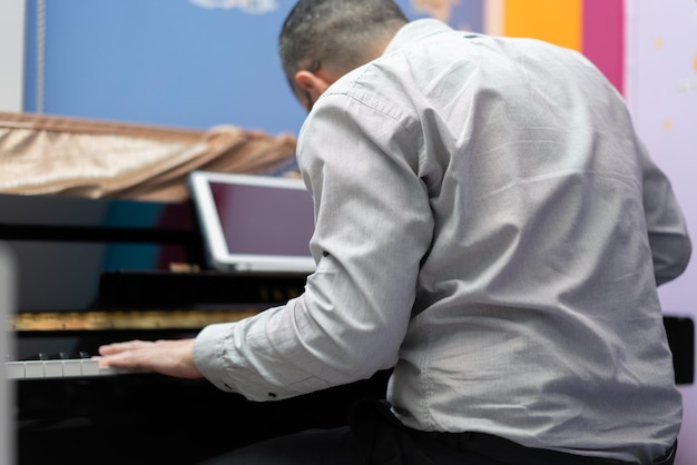 Homem toca piano da vista traseira do aprendizado on-line