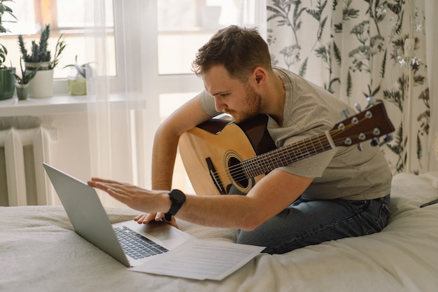 Homem toca violão em uma aula online