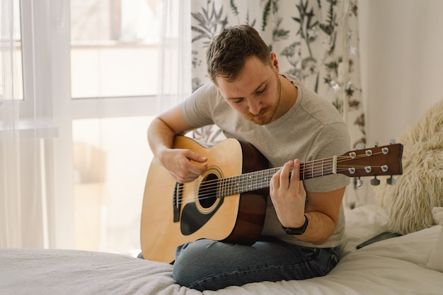 Homem toca violão em uma sala de casa