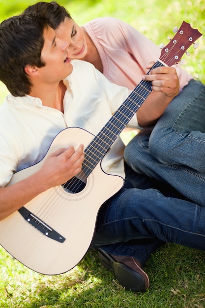 Homem tocando guitarra enquanto o amigo se inclina no ombro