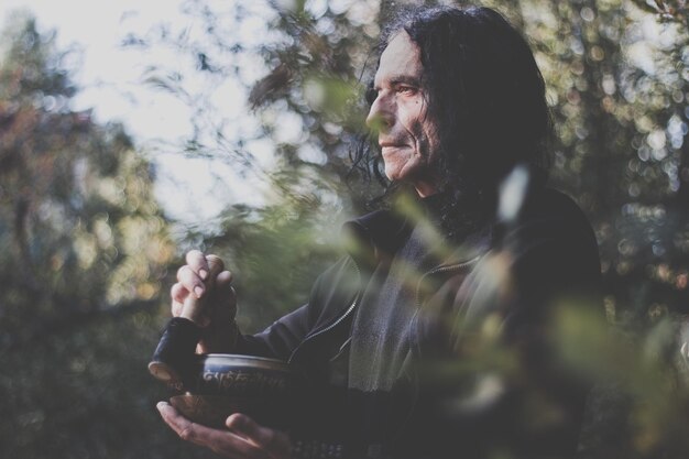 Foto homem tocando rin gong enquanto está de pé na floresta