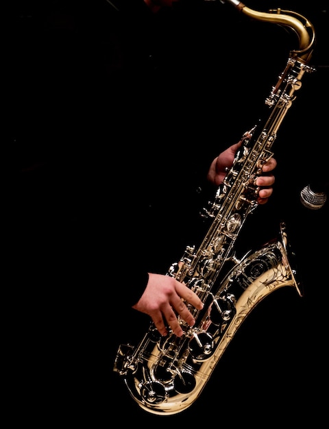 Homem tocando saxofone contra fundo preto