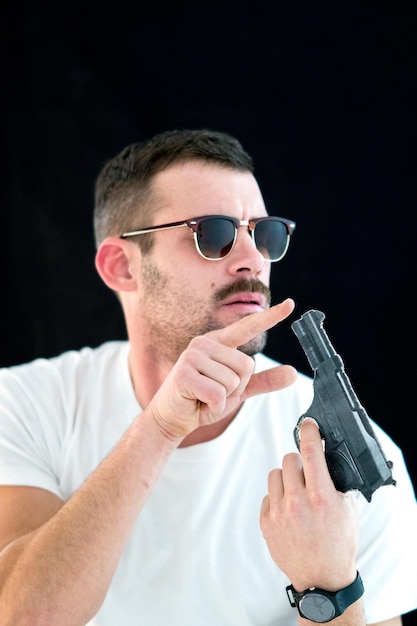 Foto homem tocando uma arma contra um fundo preto