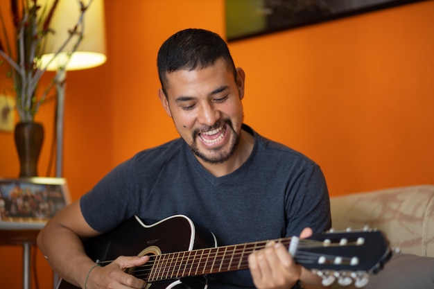 Homem tocando violão em casa