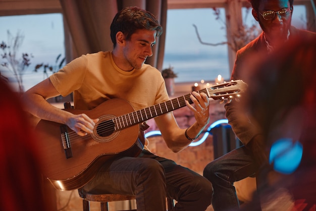 Homem tocando violão para seus amigos