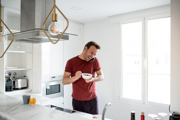 Homem tomando café da manhã com telefone celular