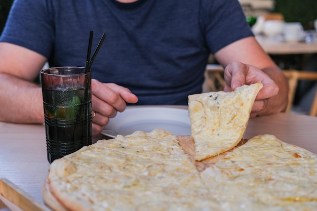 Homem tomando pedaço de pizza no café Pizza com pêra e queijo