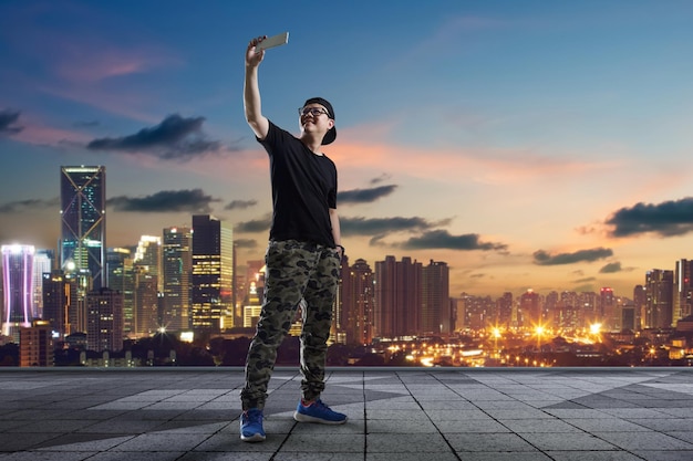 Homem tomando selfie no telhado no fundo do horizonte da cidade