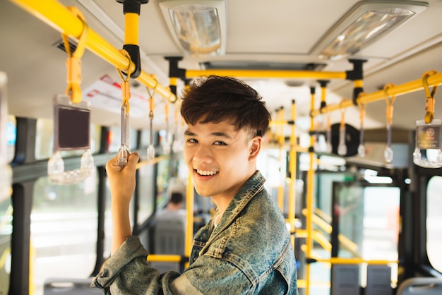 Homem tomando transporte público, em pé dentro de ônibus