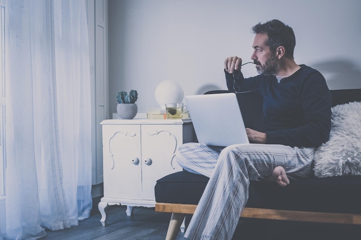Foto homem trabalha com laptop sentado no sofá homem em casa trabalhando com menino de escritório remoto na sala de estar