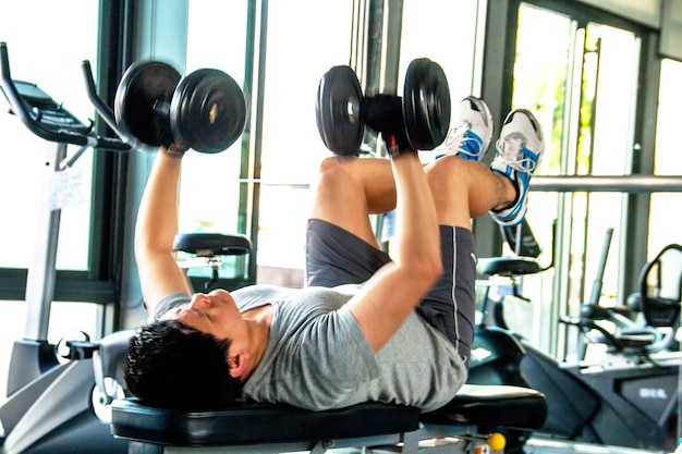 Homem trabalha com sinos de despejo em fitness