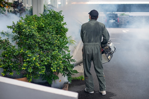 Foto homem trabalha nebulizando para eliminar mosquitos para prevenir a propagação da dengue